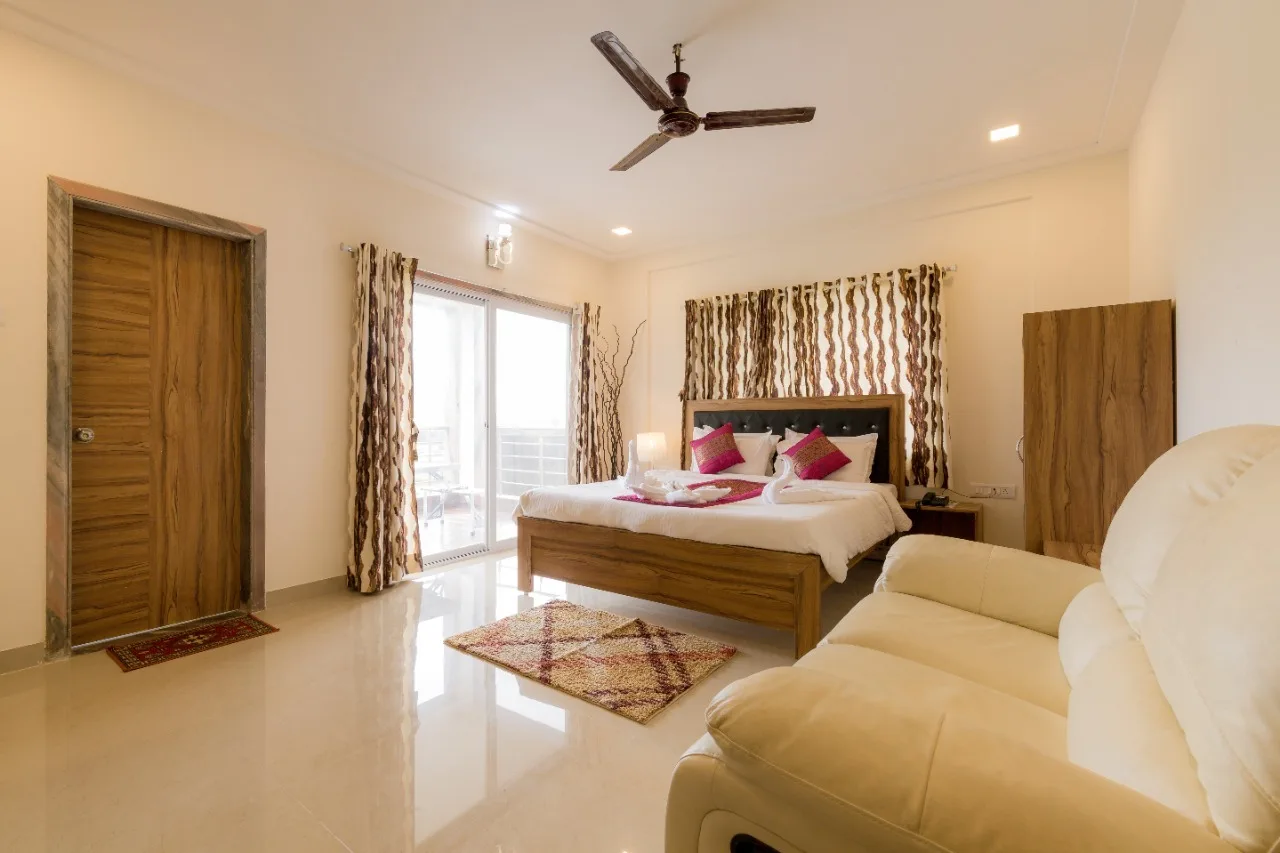 Luxurious hotel room with a cozy bed and large windows offering a breathtaking view of the mountains.